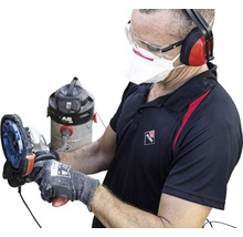 Handwerker mit Schleifmaschine, Staubmaske, Schutzbrille und Gehörschutz