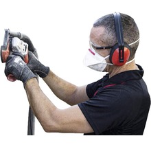 Mann mit Gehörschutz, Schutzbrille und Staubmaske bedient eine Mauernutfräse.