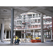 Bauarbeiter misst eine Stahlsäule auf einer Baustelle.
