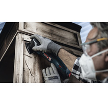 Mann arbeitet mit einem Multifunktionswerkzeug an einem Holzschrank.