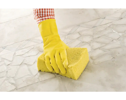 Person mit Gummihandschuh und Schwamm reinigt Fliesenboden.