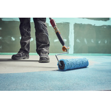 Handwerker streicht Boden mit Farbroller