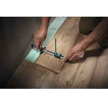 Zimmerer, der mit einem Anreißwerkzeug einen Laminatboden verlegt