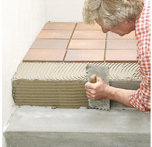 Fliesenleger bei der Arbeit, Fliesen werden auf einer Treppe verlegt.