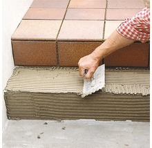 Verlegung von Fliesen auf einer Treppe mit einer Kelle.