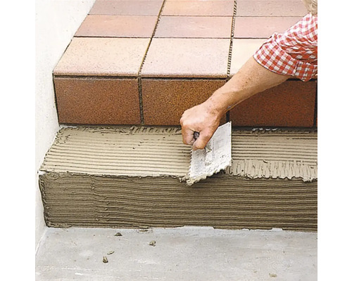 Verlegung von Fliesen auf einer Treppe mit einer Kelle.