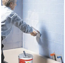 Fliesenleger bei der Arbeit im Badezimmer mit Fliesenkleber und Kelle