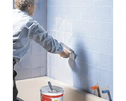 Fliesenleger bei der Arbeit im Badezimmer mit Fliesenkleber und Kelle