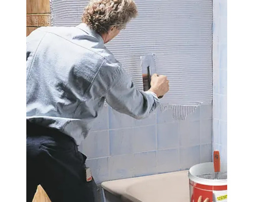 Fliesenleger bei der Arbeit: Anbringen von Fliesen an der Wand mit einem Spachtel