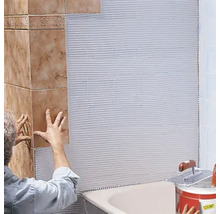 Fliesenleger bei der Arbeit im Badezimmer mit Fliesenkleber, Fliesen und Werkzeugen