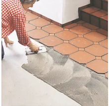Fliesenleger verlegt Bodenfliesen mit Fliesenkleber