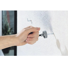 Eine Person befestigt einen Dübel mit einem Montagewerkzeug an einer Wand