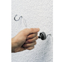 Hand dreht eine Schraube in eine Wand neben einem Haken