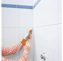 Eine Person trägt Dichtmasse mit einer Kartuschenpistole auf Fliesenfugen auf