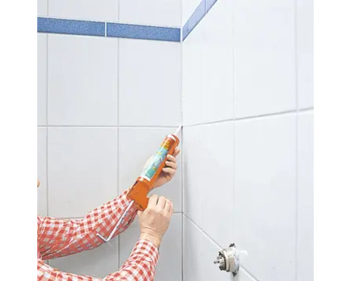 Eine Person trägt Dichtmasse mit einer Kartuschenpistole auf Fliesenfugen auf