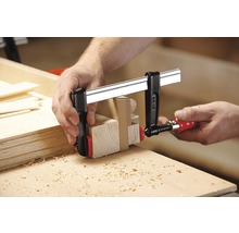 Holzbearbeitung mit einer Schraubzwinge zum Fixieren von Holzteilen.