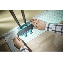 Wolfcraft Logo. Eine Person verwendet eine Anreißlehre zum Anzeichnen von Heizungsrohren auf einer Dämmunterlage.