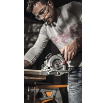 Mann sägt Holzbrett mit Handkreissäge auf einer Werkbank