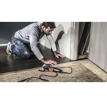 Ein Mann arbeitet mit einem Multifunktionswerkzeug von Worx an einem Bodenbelag.