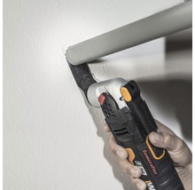 Eine Hand bedient einen Multifunktionsschneider zum Schneiden eines Rohres an einer Wand.