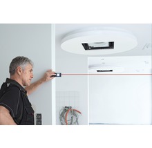 Handwerker misst mit Laser-Distanzmessgerät einen Raum.