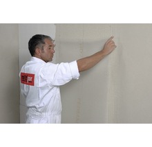 Ein Mann bringt an einer Wand eine Dämmplatte an