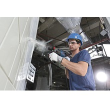 Ein Bauarbeiter bohrt mit einem Bohrhammer in eine Wand.