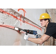 Ein Bauarbeiter bohrt mit einem Bohrhammer ein Loch in eine Wand.