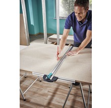 Ein Mann markiert mit einem Bleistift eine Gipsplatte mit einem Schneidwerkzeug auf einem Tisch