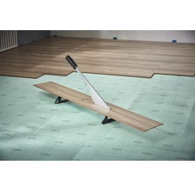 Laminatschneider schneidet Laminatdiele auf Dämmunterlage
