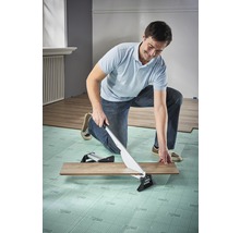 Ein Mann schneidet mit einem Laminatschneider eine Laminatdiele.