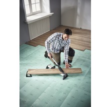 Mann verlegt Laminat mit Laminatschneider auf Trittschalldämmung