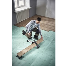 Mann schneidet Laminat mit Laminatschneider auf Trittschalldämmung