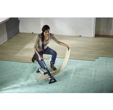 Frau schneidet Laminat mit einem Laminatschneider auf einem Unterlagsboden