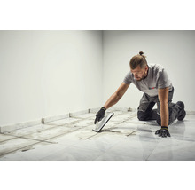 Ein Mann verfugt Fliesen im Innenraum.