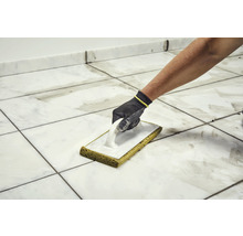 Fliesenleger reinigt Fliesen mit Schwammbrett