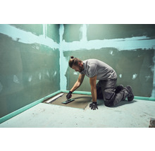 Handwerker bei der Arbeit an einer bodengleichen Dusche mit Spachtel