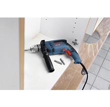 Bohrmaschine mit Bohrer, Dübeln und Scharnier vor einem Schrank