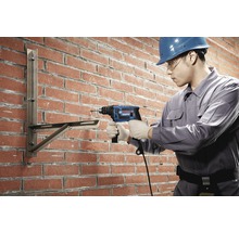 Handwerker bohrt mit einer Schlagbohrmaschine in eine Ziegelwand