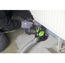 Mann verwendet einen Betonsanierfräser an einem Heizkörper auf dem Boden