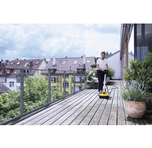 Frau reinigt Holzterrasse mit Terrassenreiniger