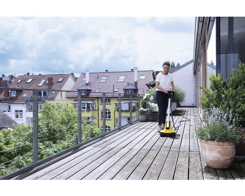 Frau reinigt Holzterrasse mit Terrassenreiniger