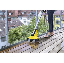 Frau reinigt Holzterrasse mit Kärcher Terrassenreiniger