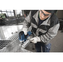 Mann mit Schutzbrille und Handschuhen sägt Metall mit einer Stichsäge