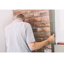 Mann bringt eine Wandverkleidung in Steinoptik an