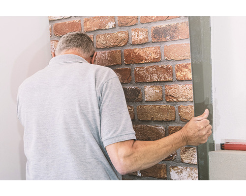 Mann bringt eine Wandverkleidung in Steinoptik an