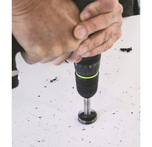 Eine Person bohrt mit einer Bohrmaschine ein Loch in eine Oberfläche.