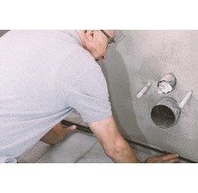 Mann verlegt Fliesenschiene im Badezimmer.