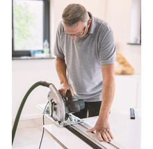 Mann sägt Holz mit einer Handkreissäge und Führungsschiene