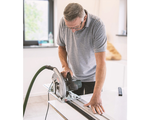 Mann sägt Holz mit einer Handkreissäge und Führungsschiene